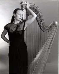 A woman in black dress holding a harp.