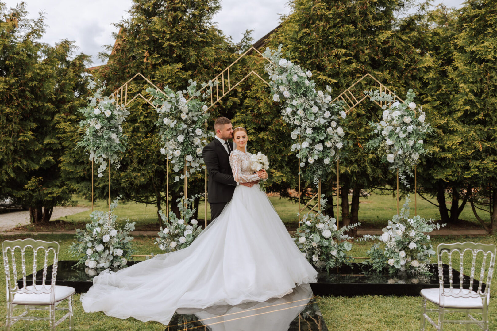 Attractive couple newlyweds, happy and joyful moment. Man and woman in festive clothes near the wedding decoration in boho style. Ceremony outdoors.